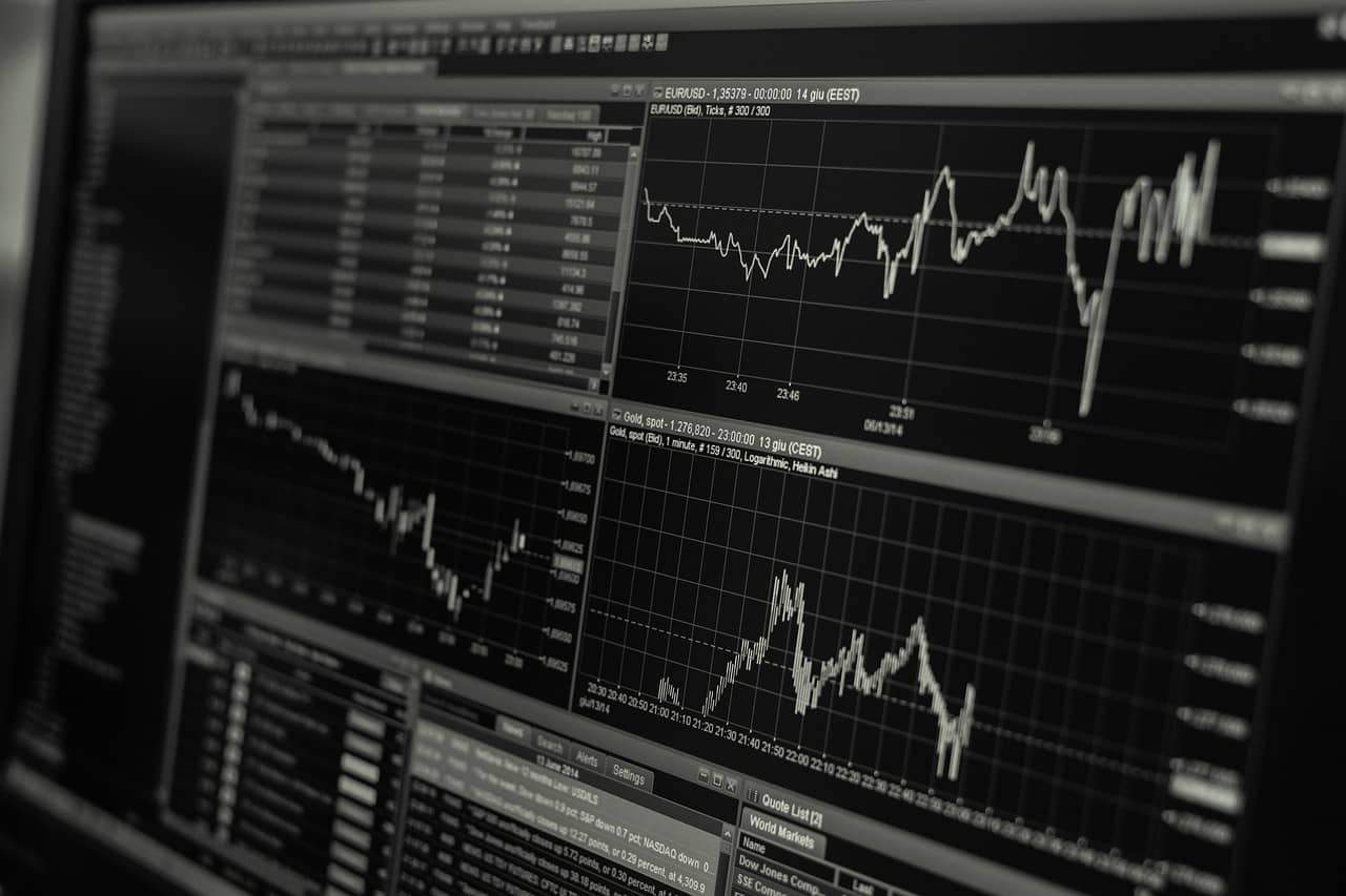 Pantalla de computadora mostrando gráficos y datos financieros con curvas de tendencia y tablas de cotizaciones en un software de trading.